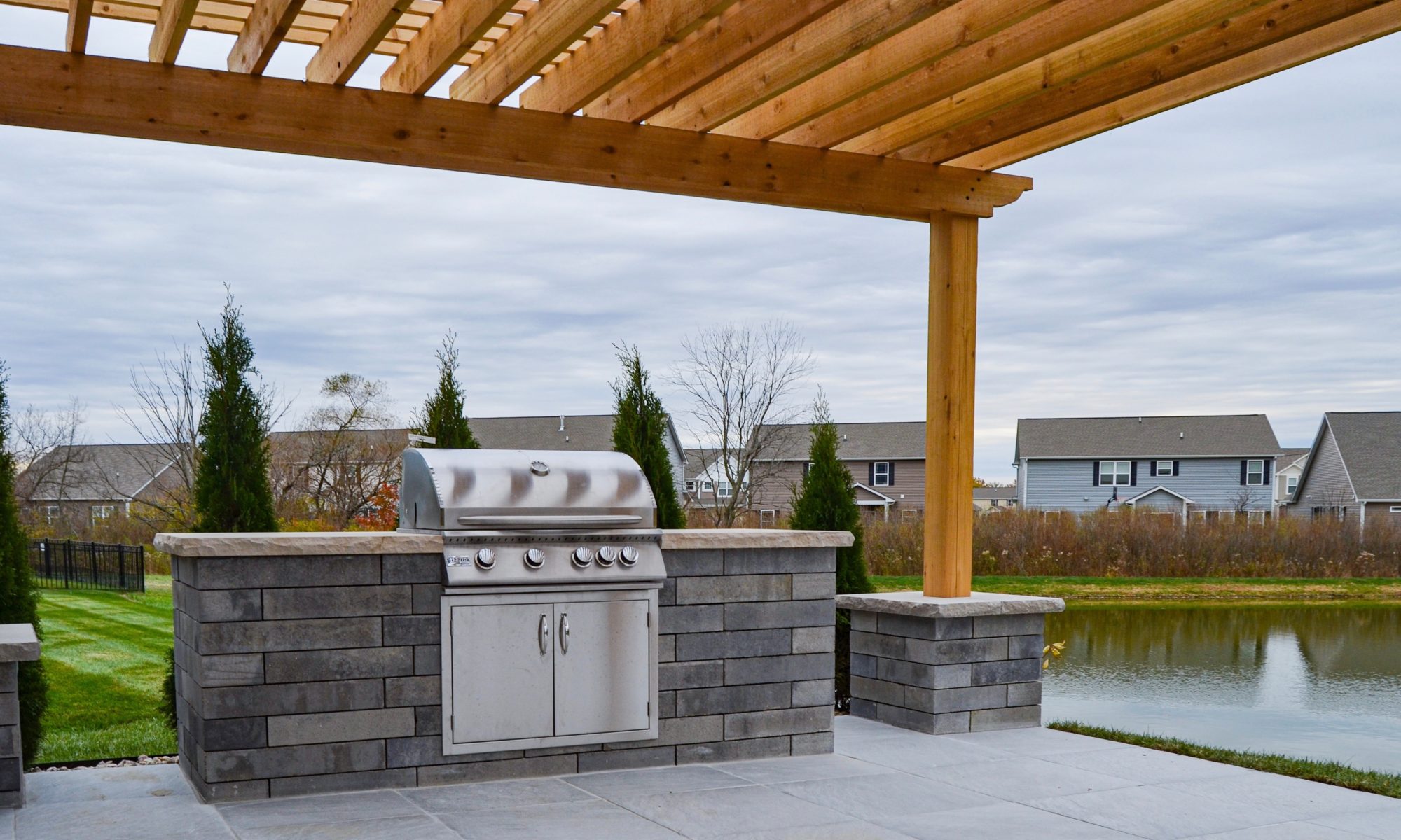 Precision Outdoors Avon Paver Patio & Pergola Exterior Design cedar pergola custom block columns porcelain paver patio built belgard Turin rapids color accents seating wall unilock lineo wall charcoal grey accents gas firepit fire pit warm gathering space instant fire switch personal grill island sizzler grill unit custom fitted double access doors Avon indiana entertaining
