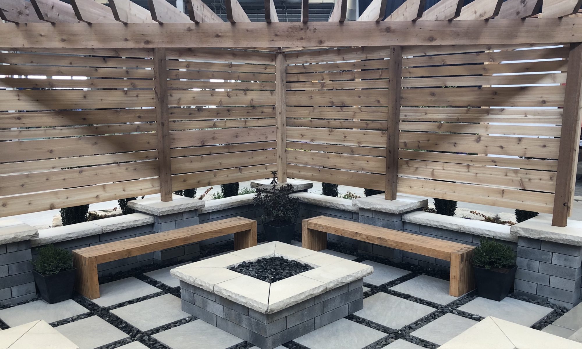 Flower and Patio Show 2019 Precision Outdoors Indianapolis Indiana sunken porcelain firepit fire pit space freestanding water wall structure cedar pergola screening walls privacy walls custom planters rough cedar pavilion gathering space outdoor kitchen grill bar space walls walkways