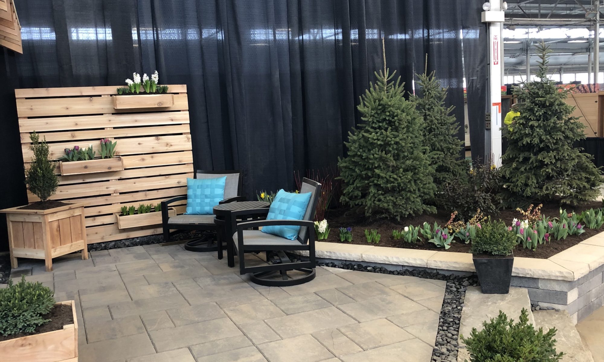 Flower and Patio Show 2019 Precision Outdoors Indianapolis Indiana sunken porcelain firepit fire pit space freestanding water wall structure cedar pergola screening walls privacy walls custom planters rough cedar pavilion gathering space outdoor kitchen grill bar space walls walkways