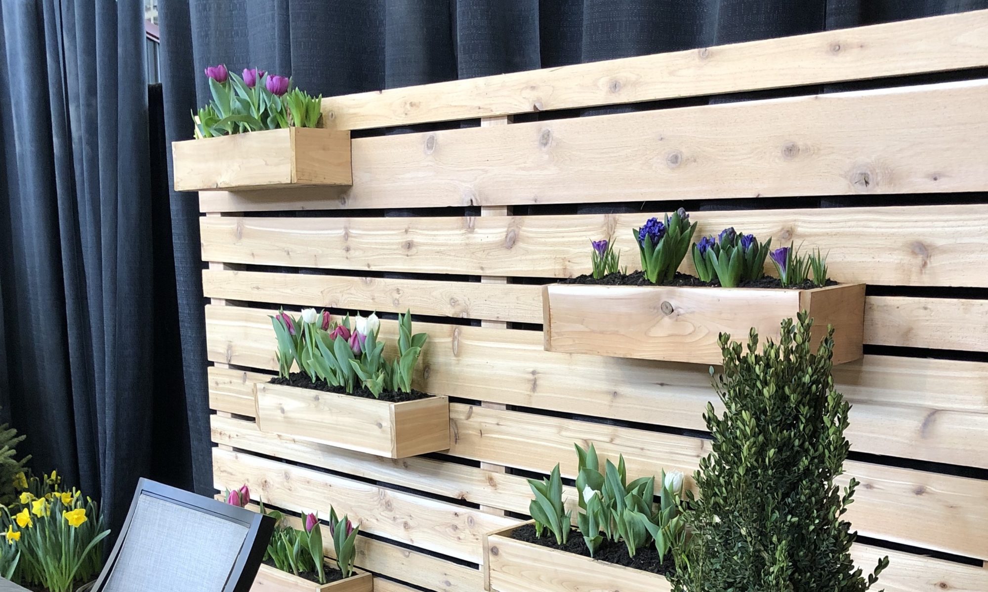 Flower and Patio Show 2019 Precision Outdoors Indianapolis Indiana sunken porcelain firepit fire pit space freestanding water wall structure cedar pergola screening walls privacy walls custom planters rough cedar pavilion gathering space outdoor kitchen grill bar space walls walkways