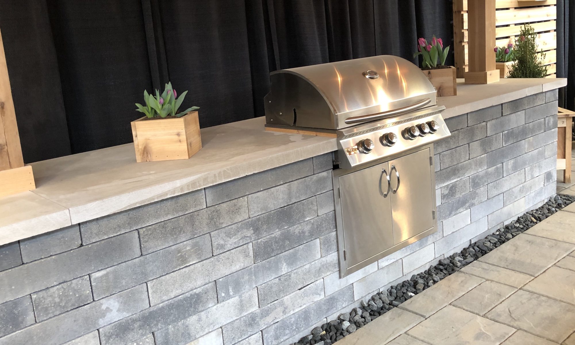 Flower and Patio Show 2019 Precision Outdoors Indianapolis Indiana sunken porcelain firepit fire pit space freestanding water wall structure cedar pergola screening walls privacy walls custom planters rough cedar pavilion gathering space outdoor kitchen grill bar space walls walkways