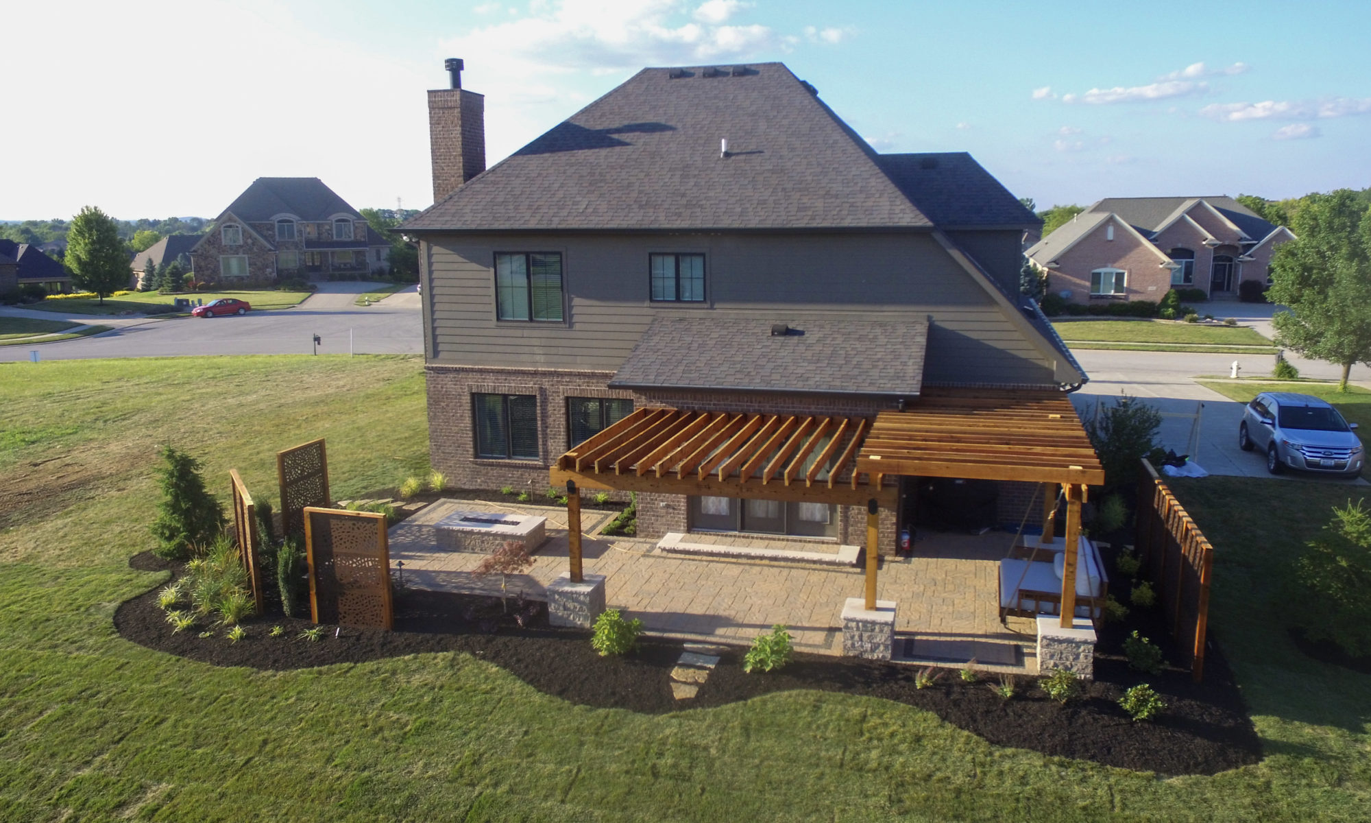 Precision Outdoors Kensington Oasis rough sawn cedar pergola black hardware decorative sunscreens outdoor gas firepit fire pit ample dining seating custom paver patio swinging daybed tech bloc semma wall sandlewood charcoal accent Carmel indiana backyard goals landscaping privacy