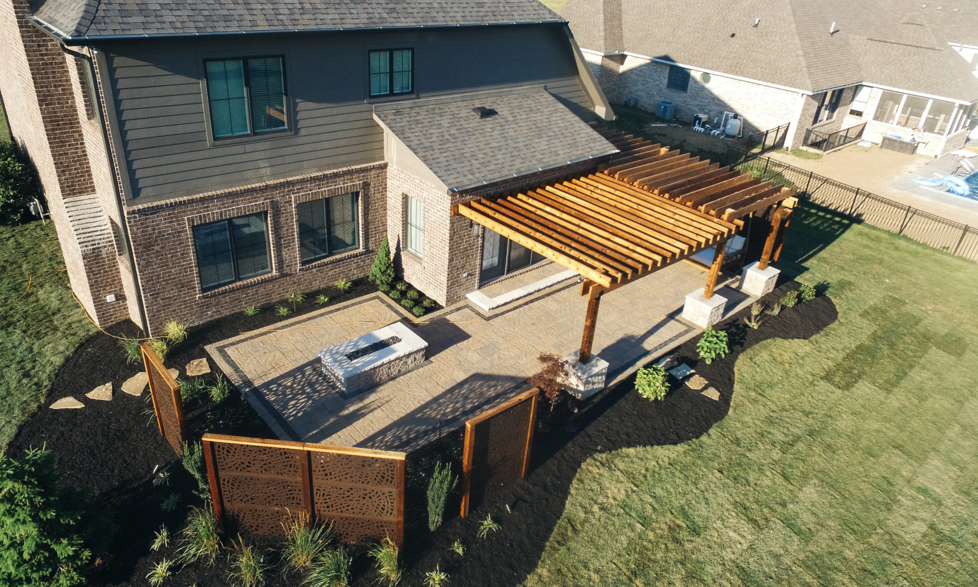 Precision Outdoors Kensington Oasis rough sawn cedar pergola black hardware decorative sunscreens outdoor gas firepit fire pit ample dining seating custom paver patio swinging daybed tech bloc semma wall sandlewood charcoal accent Carmel indiana backyard goals landscaping privacy