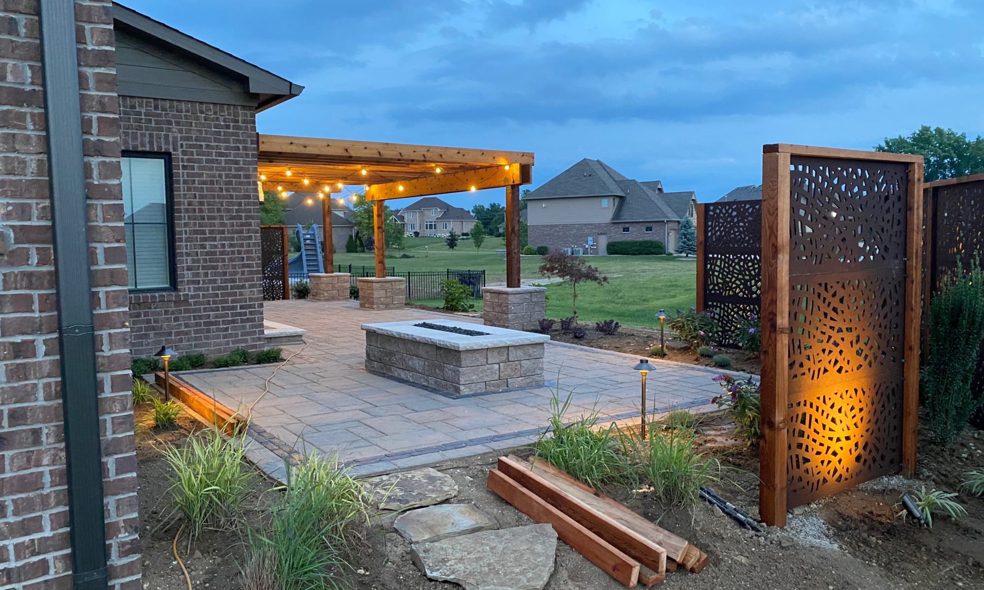 Precision Outdoors Kensington Oasis rough sawn cedar pergola black hardware decorative sunscreens outdoor gas firepit fire pit ample dining seating custom paver patio swinging daybed tech bloc semma wall sandlewood charcoal accent Carmel indiana backyard goals landscaping privacy