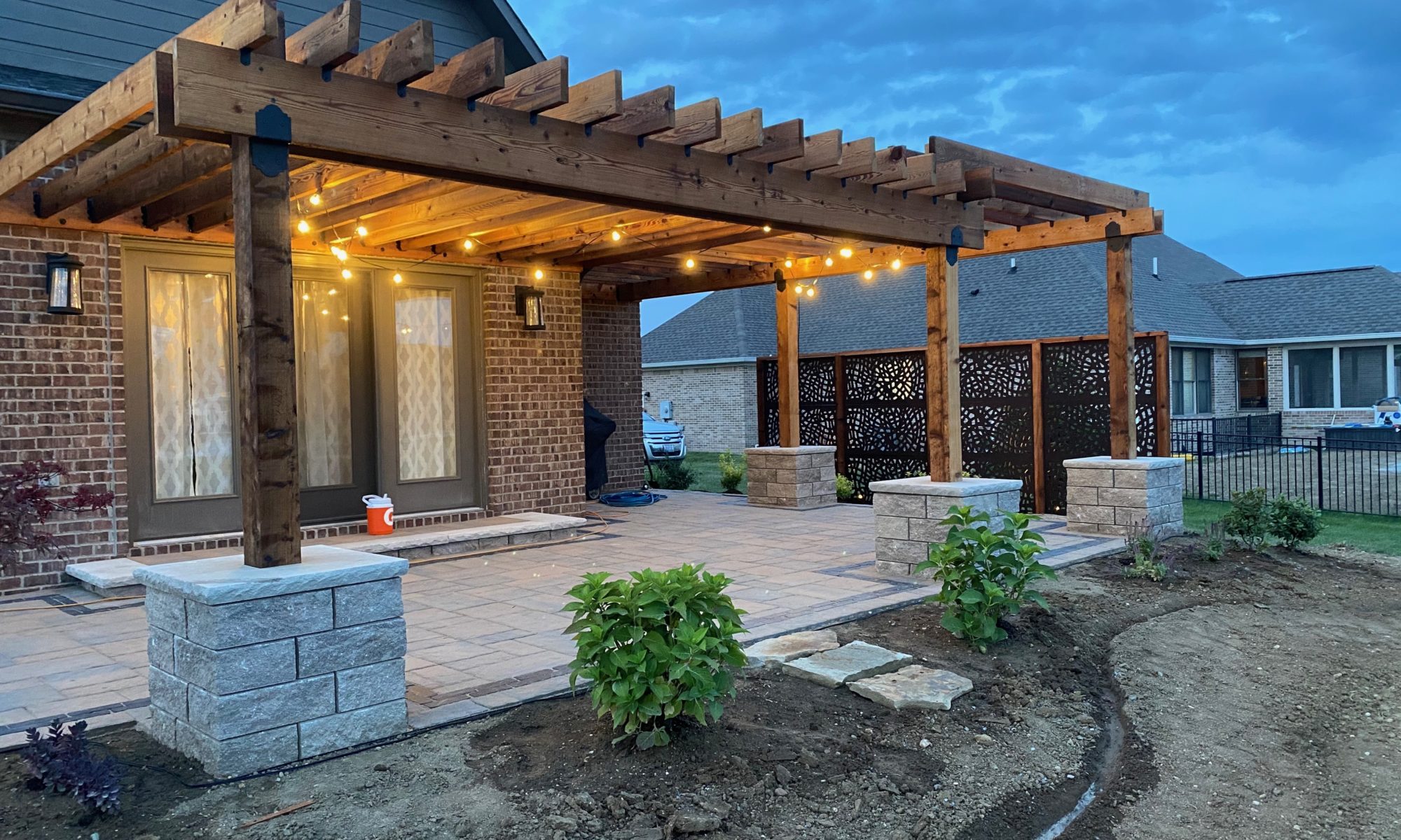 Precision Outdoors Kensington Oasis rough sawn cedar pergola black hardware decorative sunscreens outdoor gas firepit fire pit ample dining seating custom paver patio swinging daybed tech bloc semma wall sandlewood charcoal accent Carmel indiana backyard goals landscaping privacy