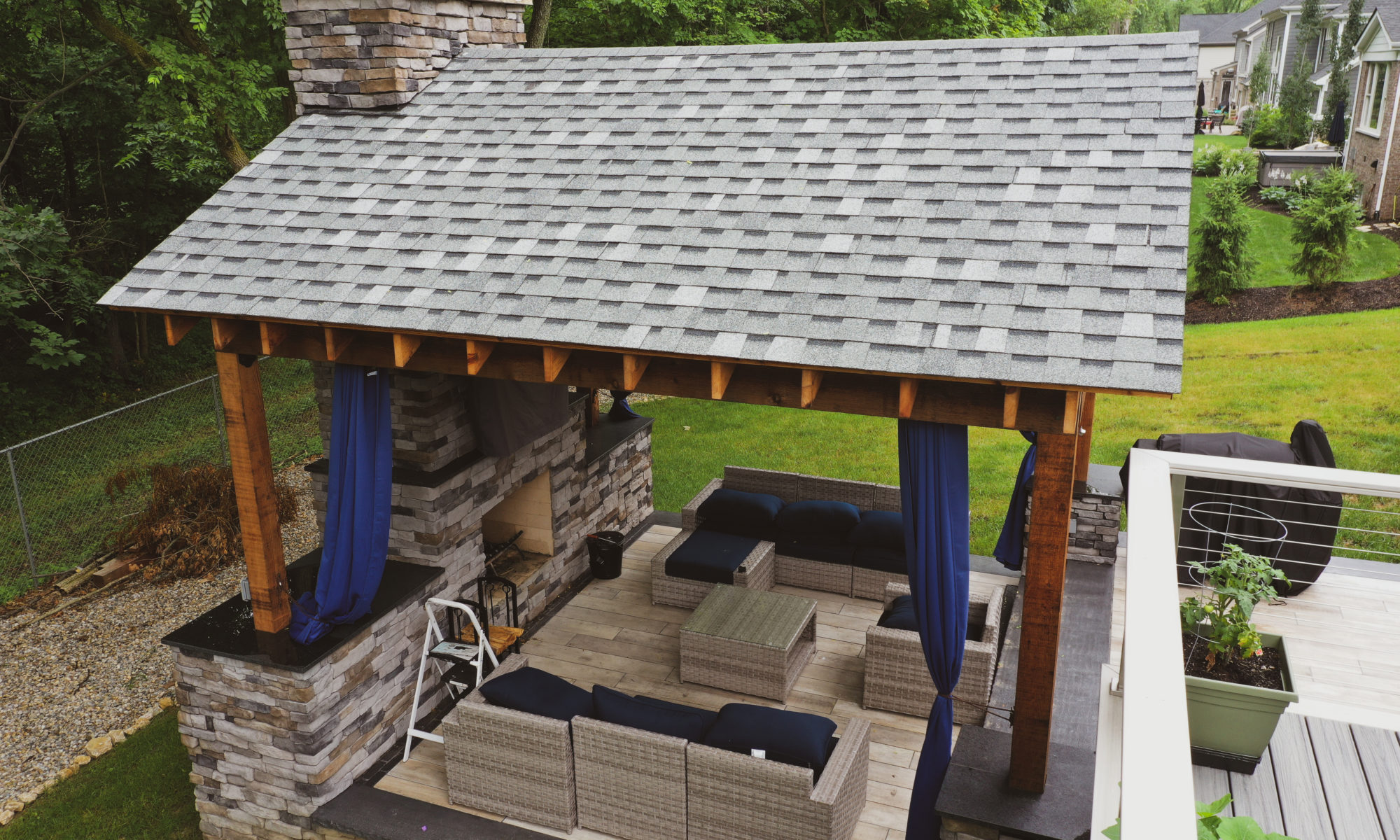 Gable Roof Structure Wood Burning Fireplace with gas fire log starter Outdoor Living by Belgard Noon tile patio Raised Deck Modern cable railing Privacy screens