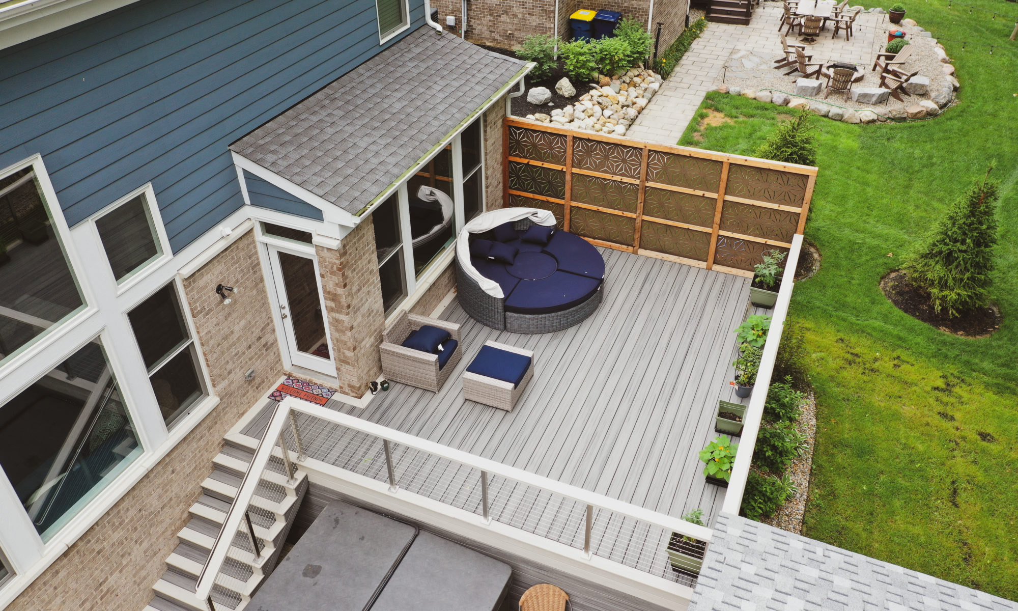 Gable Roof Structure Wood Burning Fireplace with gas fire log starter Outdoor Living by Belgard Noon tile patio Raised Deck Modern cable railing Privacy screens