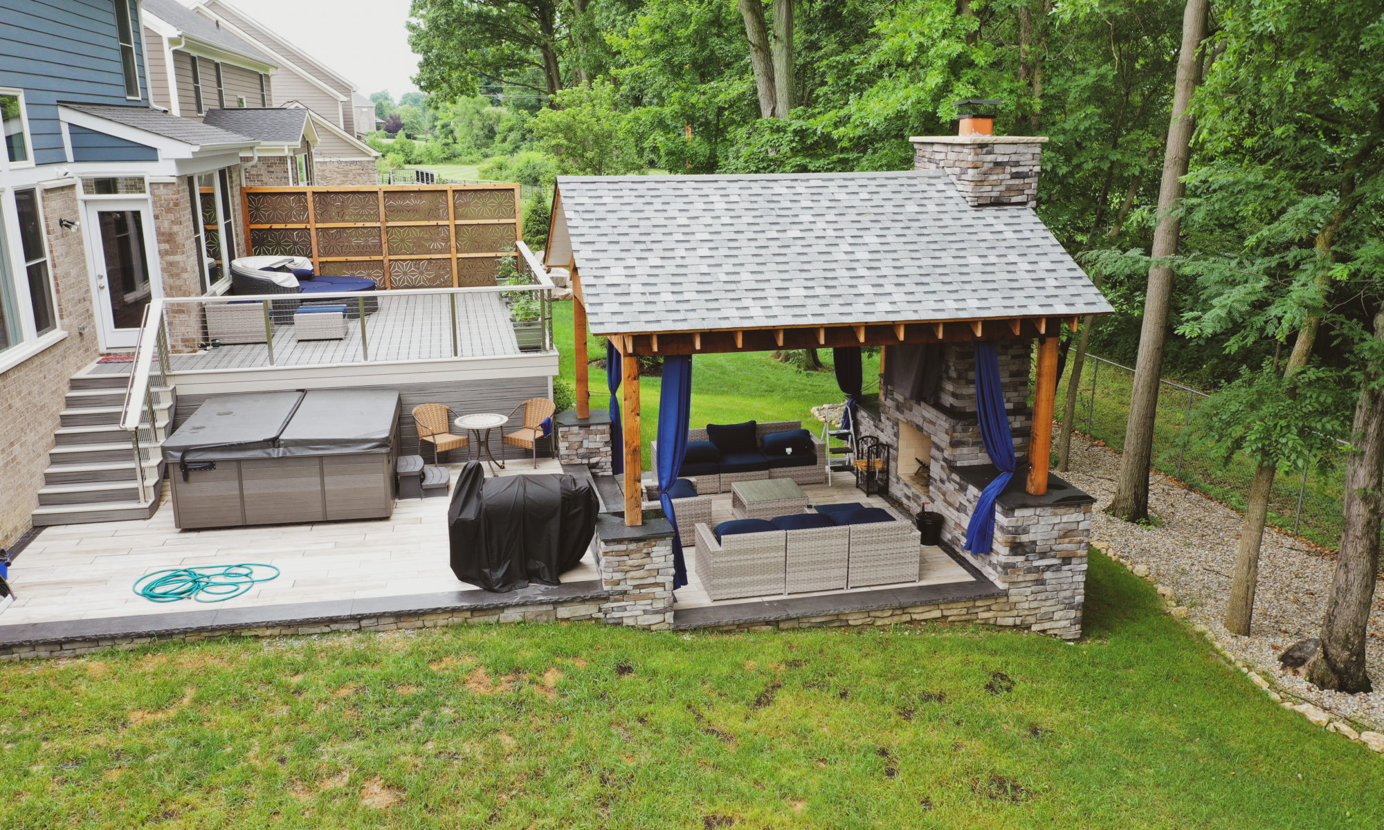 Gable Roof Structure Wood Burning Fireplace with gas fire log starter Outdoor Living by Belgard Noon tile patio Raised Deck Modern cable railing Privacy screens
