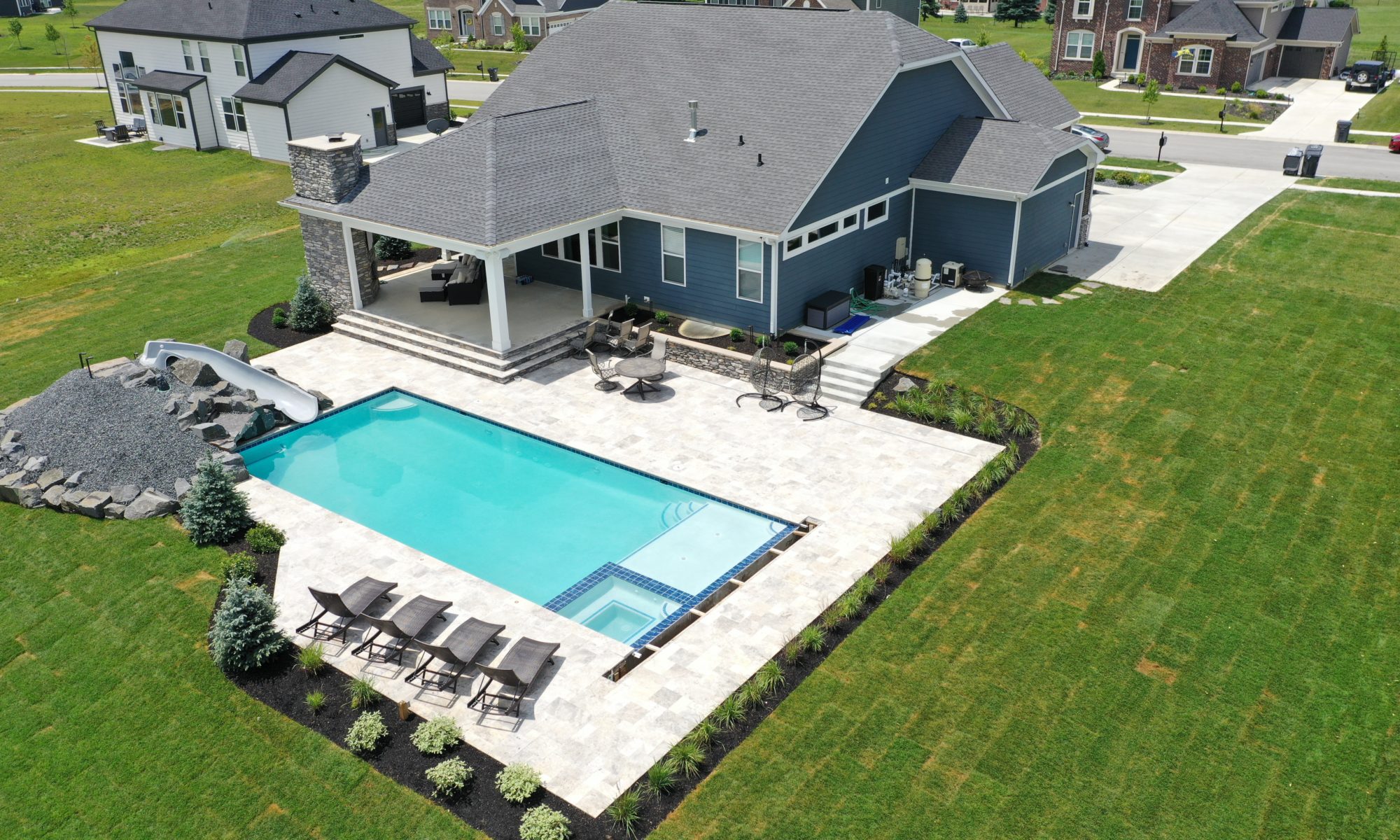 poolside pavilion paver patio pool fire fireplace stairs cover gray grey tanning deck graven plants trees flowers black