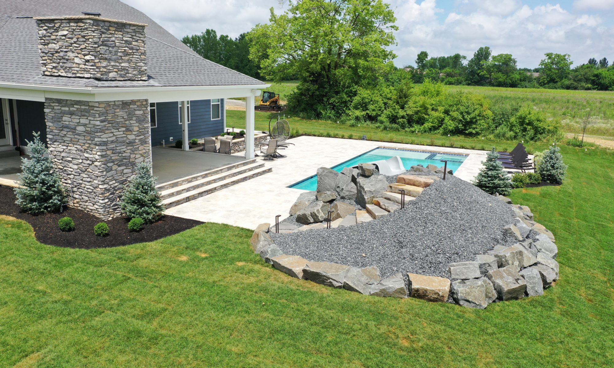 poolside pavillion paver patio pool fire fireplace stairs cover gray grey tanning deck graven plants trees flowers black