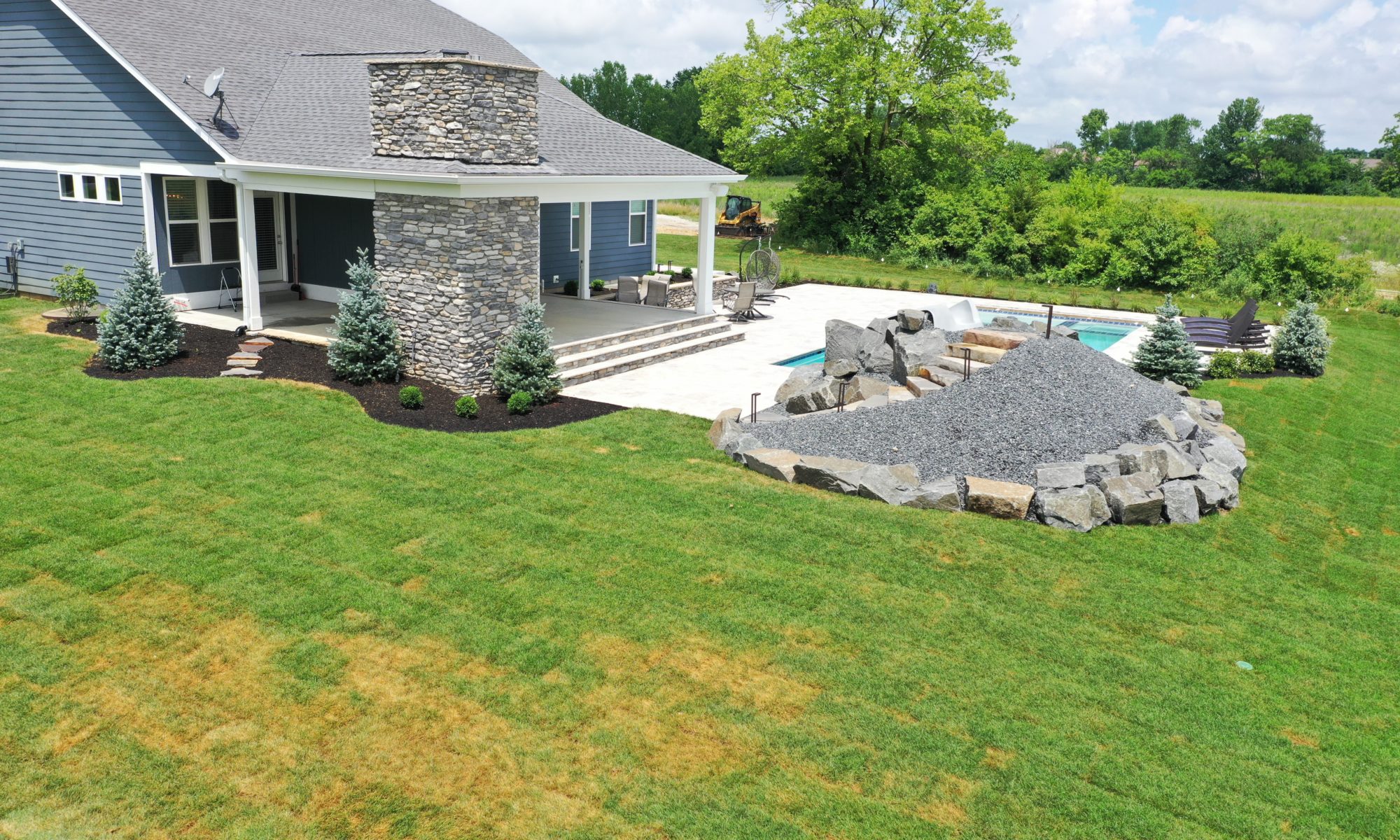 poolside pavillion paver patio pool fire fireplace stairs cover gray grey tanning deck graven plants trees flowers black