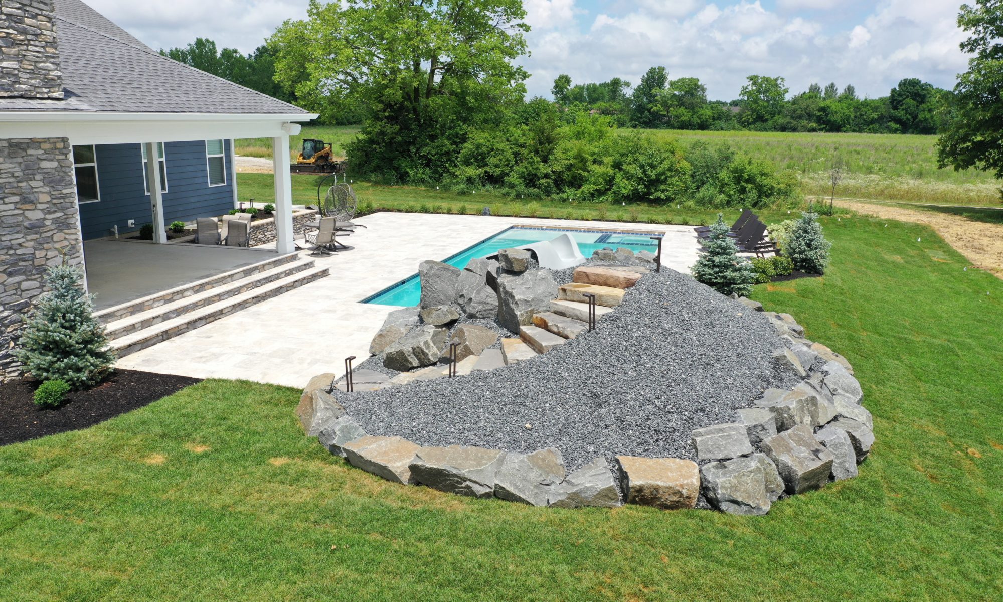 poolside pavillion paver patio pool fire fireplace stairs cover gray grey tanning deck graven plants trees flowers black