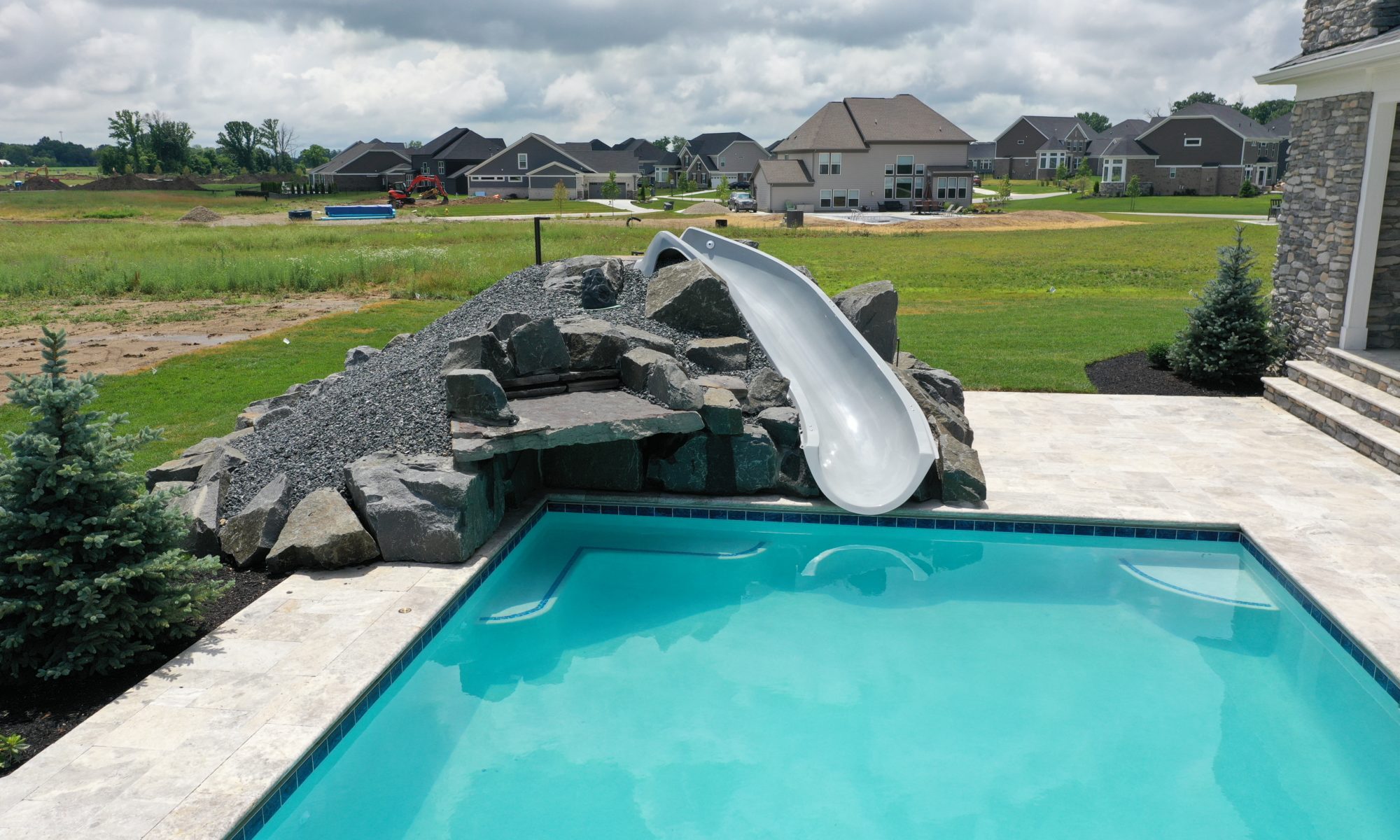 poolside pavilion paver patio pool fire fireplace stairs cover gray grey tanning deck graven plants trees flowers black