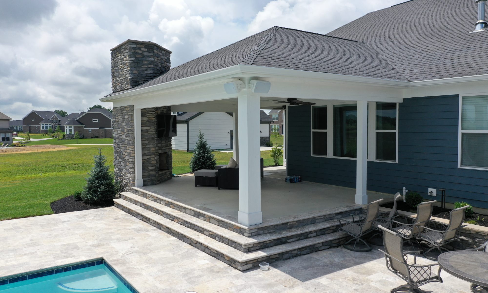poolside pavilion paver patio pool fire fireplace stairs cover gray grey tanning deck graven plants trees flowers black