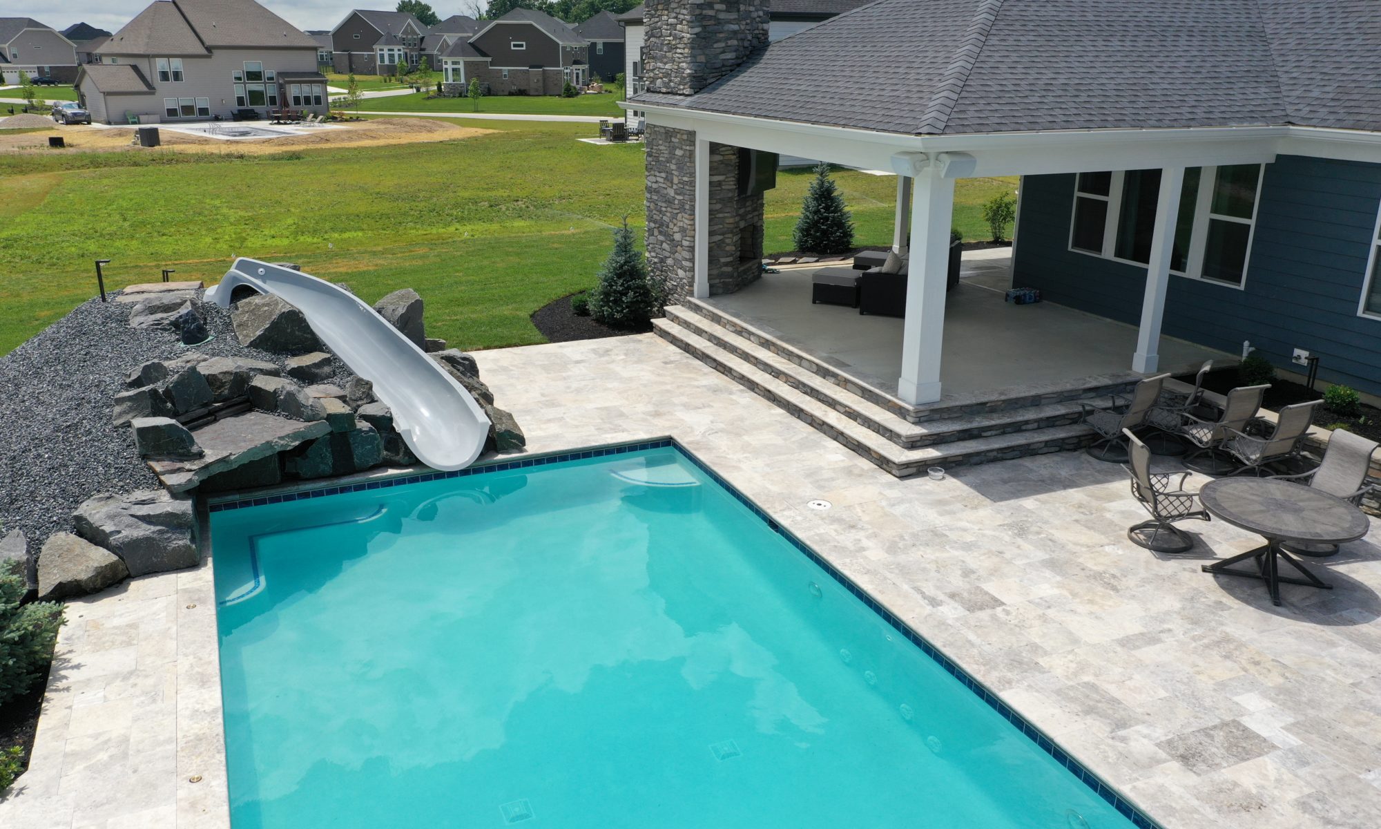 poolside pavillion paver patio pool fire fireplace stairs cover gray grey tanning deck graven plants trees flowers black