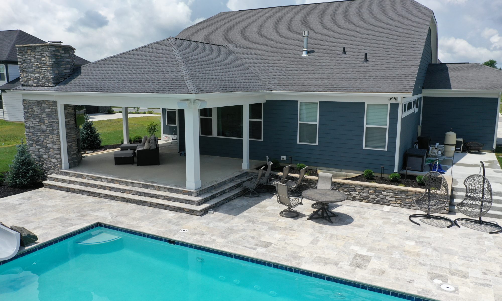 poolside pavillion paver patio pool fire fireplace stairs cover gray grey tanning deck graven plants trees flowers black