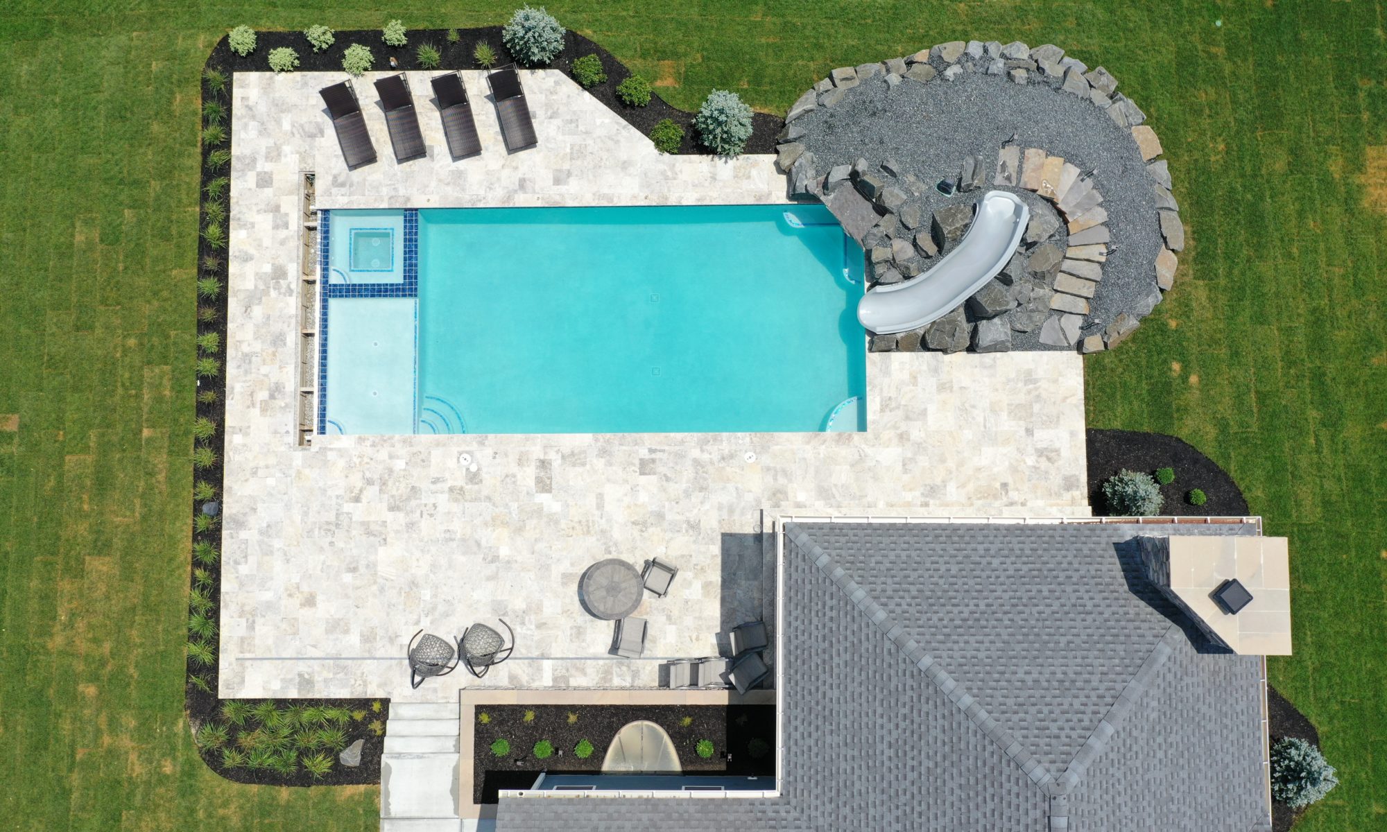 poolside pavillion paver patio pool fire fireplace stairs cover gray grey tanning deck graven plants trees flowers black