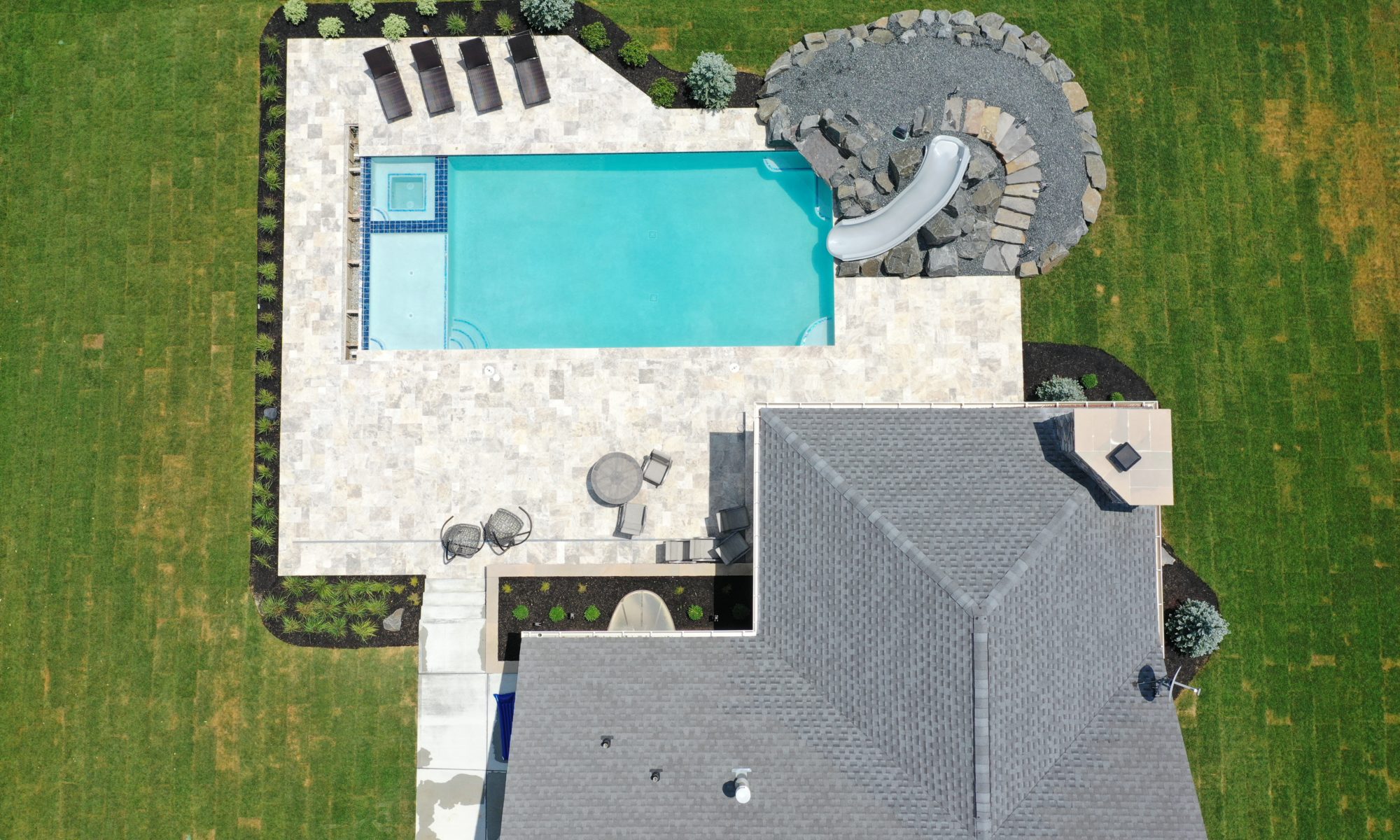 poolside pavilion paver patio pool fire fireplace stairs cover gray grey tanning deck graven plants trees flowers black