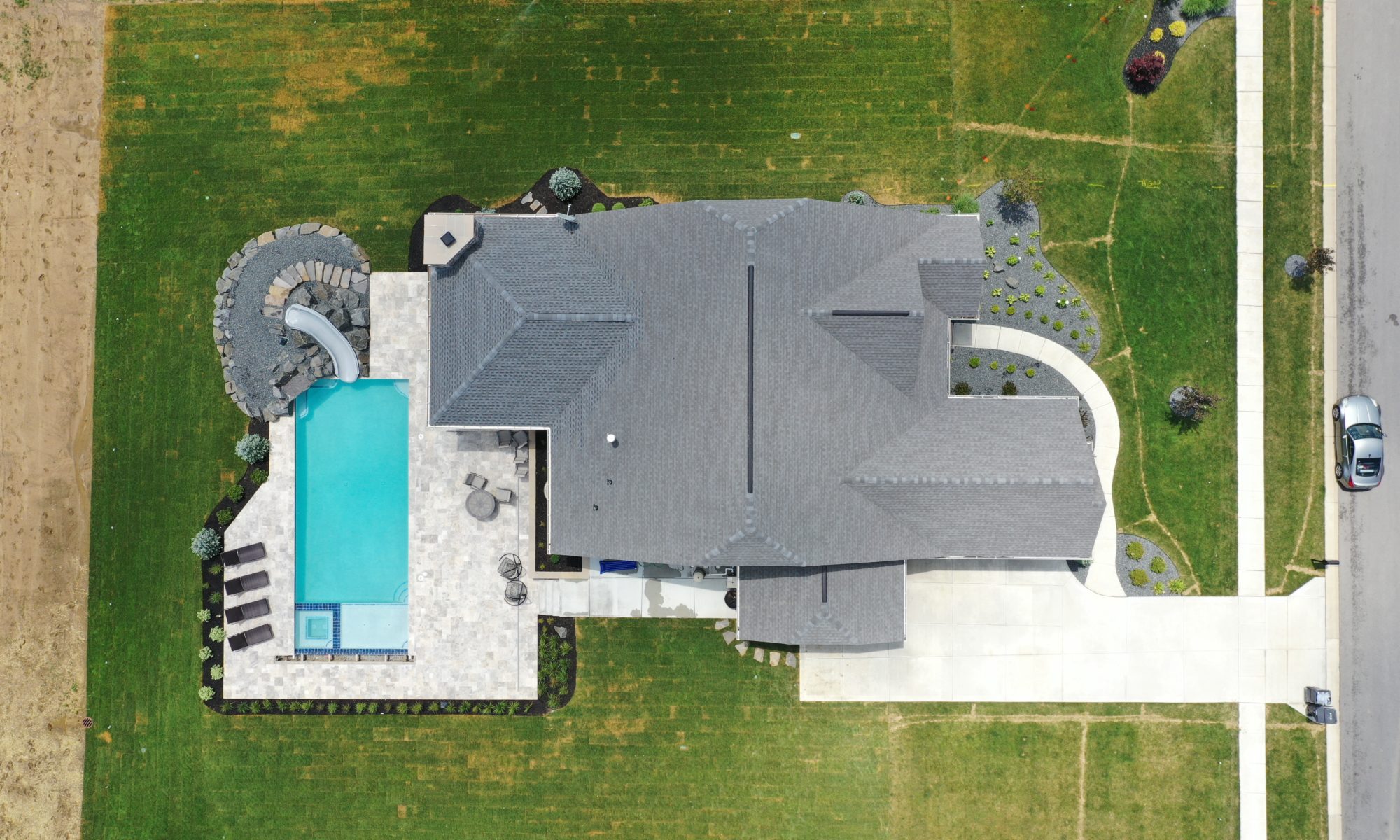 poolside pavillion paver patio pool fire fireplace stairs cover gray grey tanning deck graven plants trees flowers black