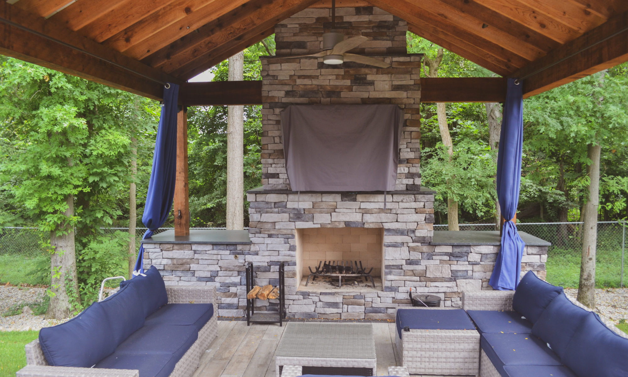 Gable Roof Structure Wood Burning Fireplace with gas fire log starter Outdoor Living by Belgard Noon tile patio Raised Deck Modern cable railing Privacy screens