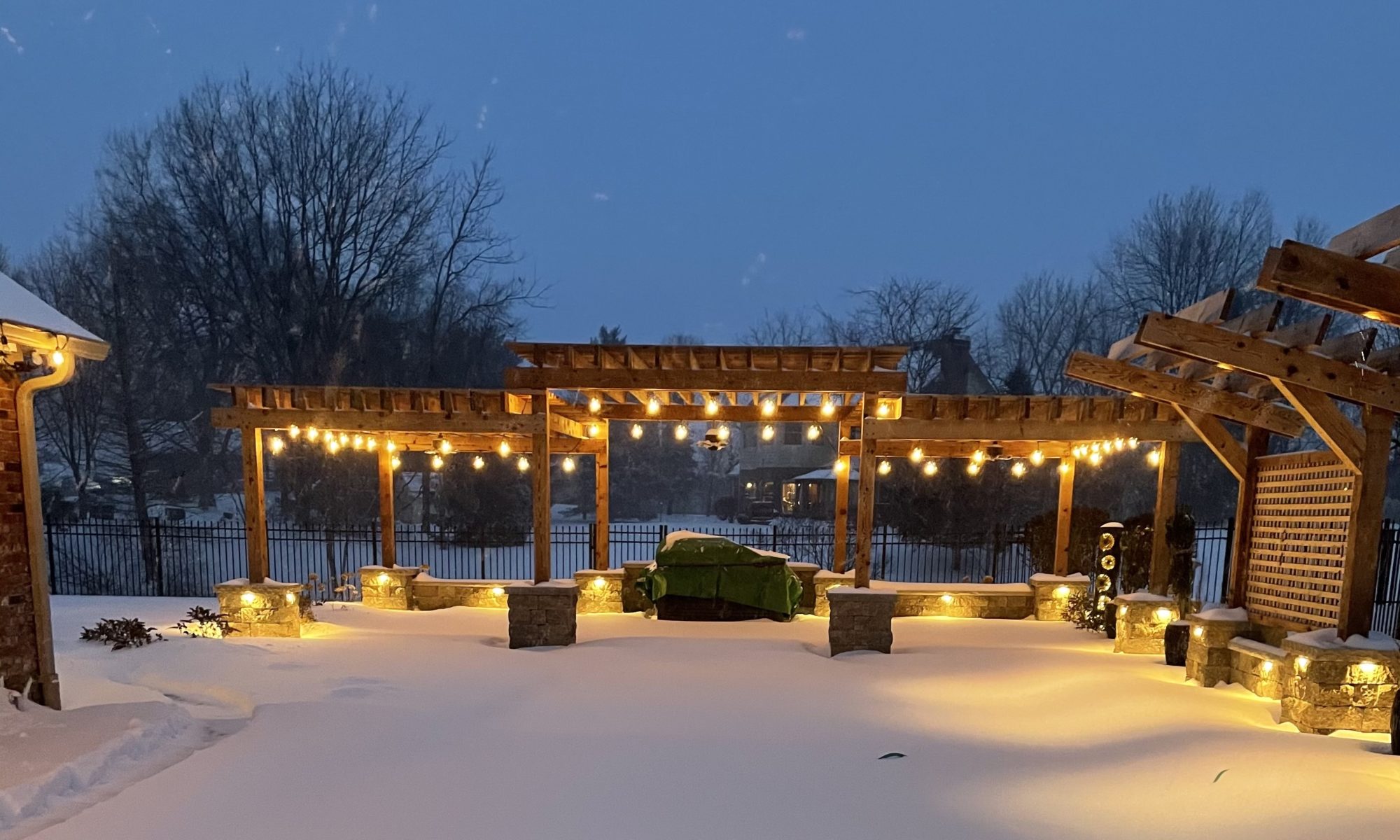 Precision Outdoors cannon cabana nights completed project night night time pool life fire table fire pit pool deck pergola outdoor kitchen timber structures retaining wall sun screens privacy screens outdoor dining entertaining space Greenwood Indiana snow winter cabana