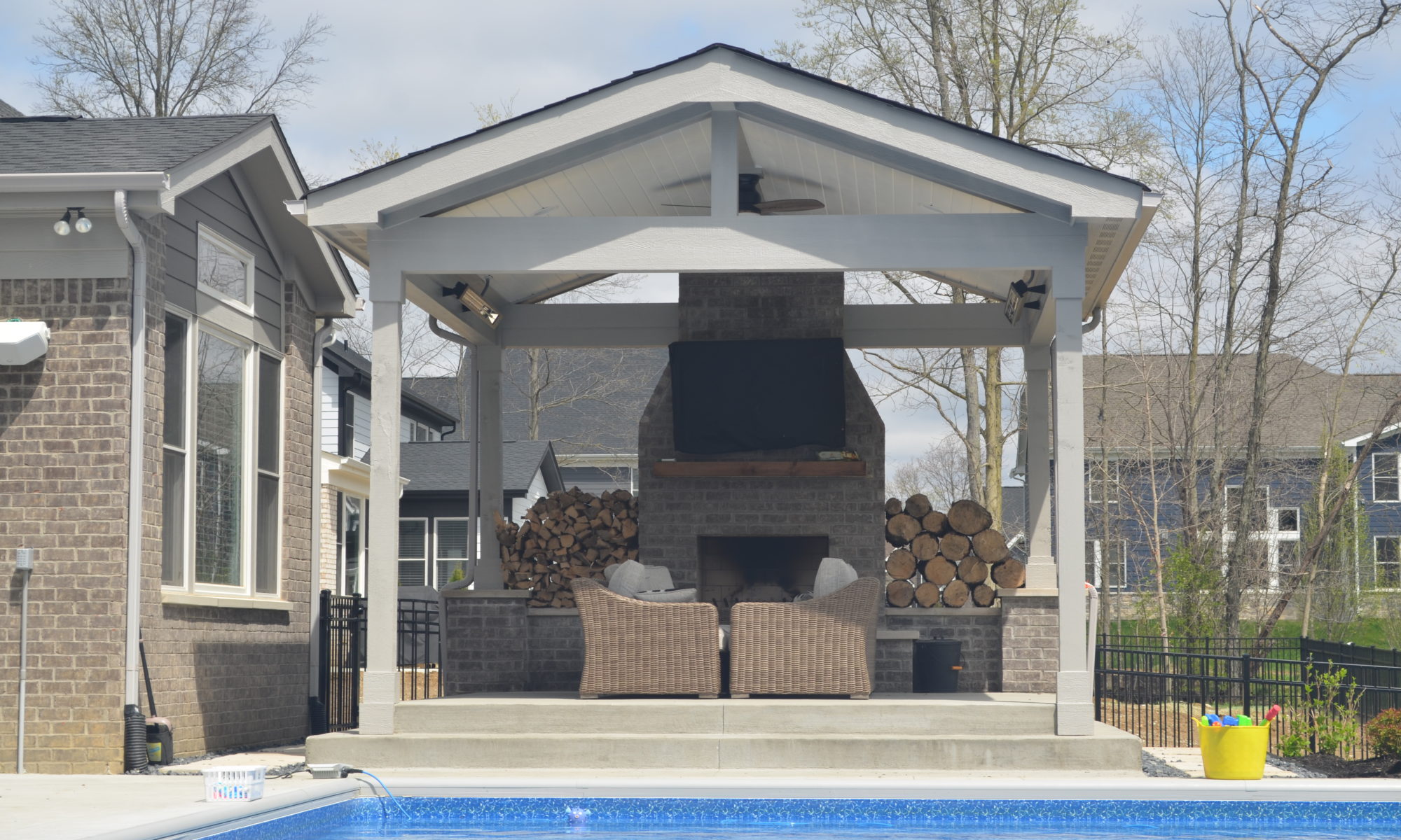 Precision Outdoors Fishers Indiana concrete patio gable sunroof structure fireplace pool custom landscaping walking stones outdoor space firewood television