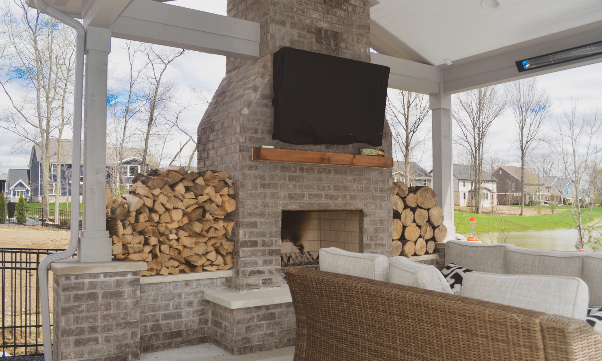 Precision Outdoors poolside at thorp creek gable roof structure fireplace fire wood storage concrete patio landscaping pool backyard summer entertaining outdoor fan heater rest and relaxation indianapolis indiana