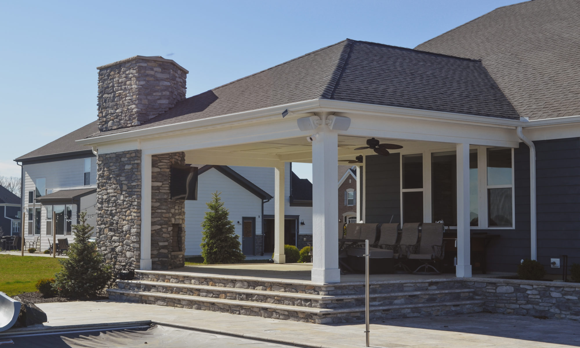 poolside pavillion paver patio pool fire fireplace stairs cover gray grey tanning deck graven plants trees flowers black