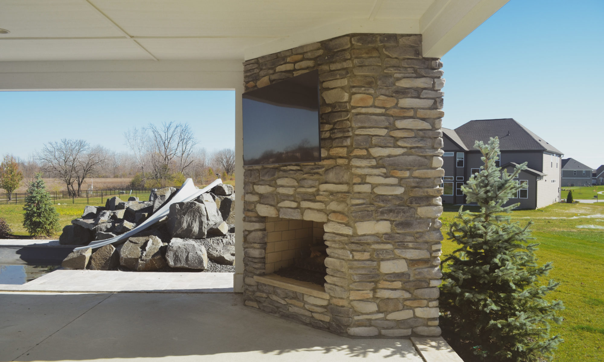 poolside pavilion paver patio pool fire fireplace stairs cover gray grey tanning deck graven plants trees flowers black