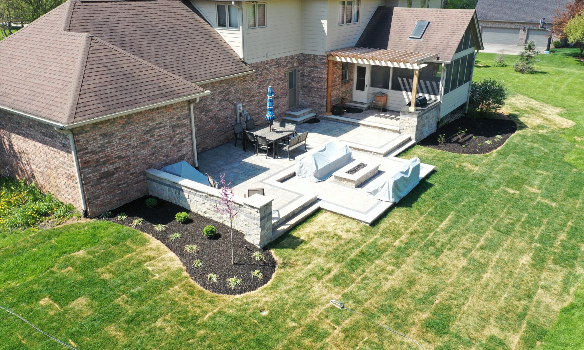 Precision Outdoors Terrace at Fox Run Zionsville Indiana Exterior design and build unilock estate wall river beacon hill flagstone alpine grey fossil unilock mattoni dark charcoal sable brown pergola outdoor kitchen gas fire pit outdoor dining area grill space several entertaining spaces large paver patio multilevel patio custom landscaping sod backyard goals mulch tree plants outdoor lighting