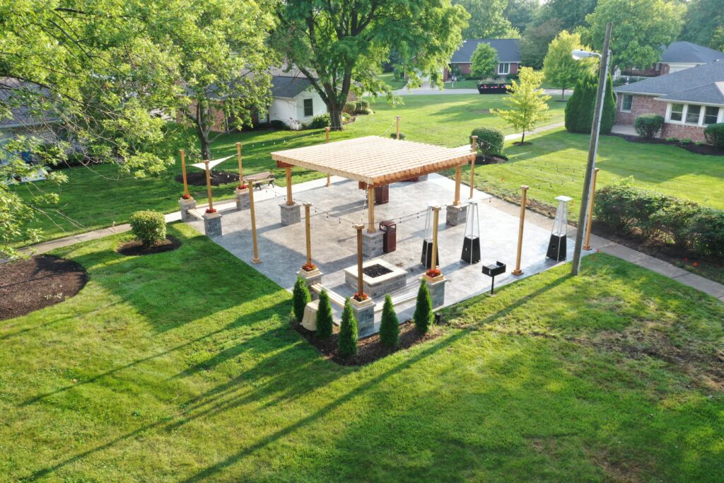 Precision Outdoors Greenwood Indiana Smock Courtyard senior living community large pergola arborvitae bubbling boulder water feature fountain propane fire pit seating corner propane heaters heat source custom landscaping flowers mulch night lighting string lights grill propane heaters flowers shared living space exterior design and build perfectly manicured turf