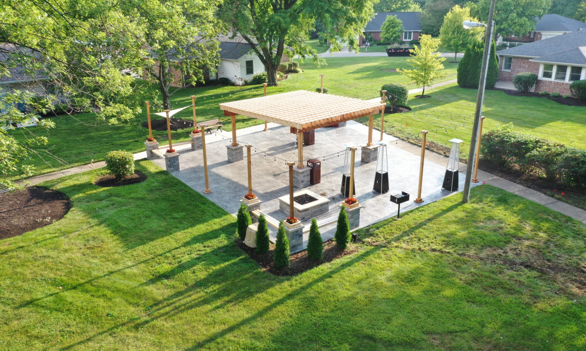 Precision Outdoors Greenwood Indiana Smock Courtyard senior living community large pergola arborvitae bubbling boulder water feature fountain propane fire pit seating corner propane heaters heat source custom landscaping flowers mulch night lighting string lights grill propane heaters flowers shared living space exterior design and build perfectly manicured turf