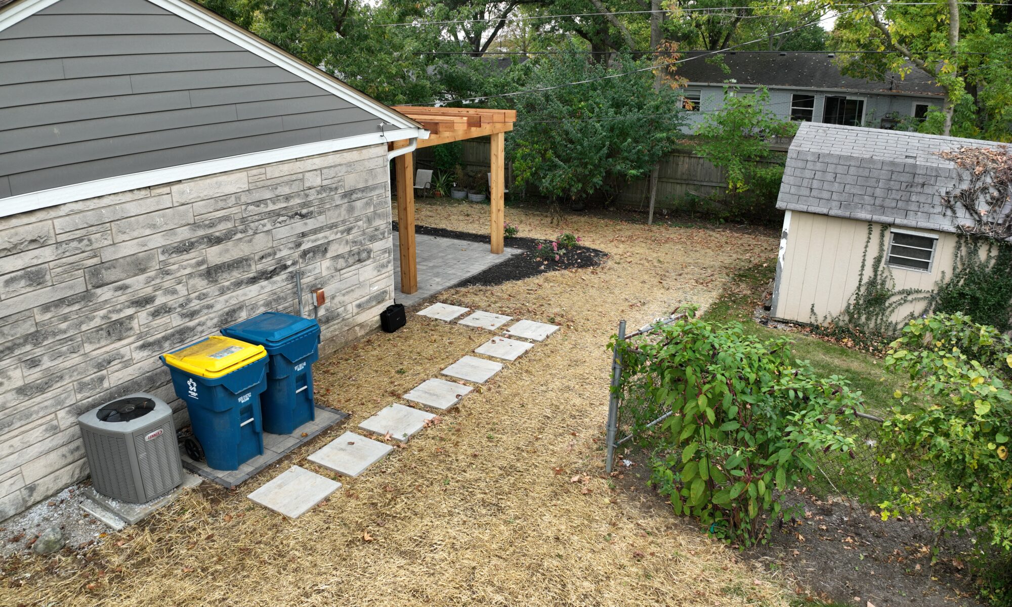 Precision Outdoors Blooming Patio Exterior design and build small patio backyard Custom cedar pergola Paver patio featuring Belgard Origins in Cotswold Mist & Belgard Dimensions Slab in Scandina Gray Custom hardscape planter box Walkway Patio steps with railing Garbage receptacle pad Custom Landscaping Carmel Indiana Trash Can pad dedicated space small narrow backyard pavers electric fan